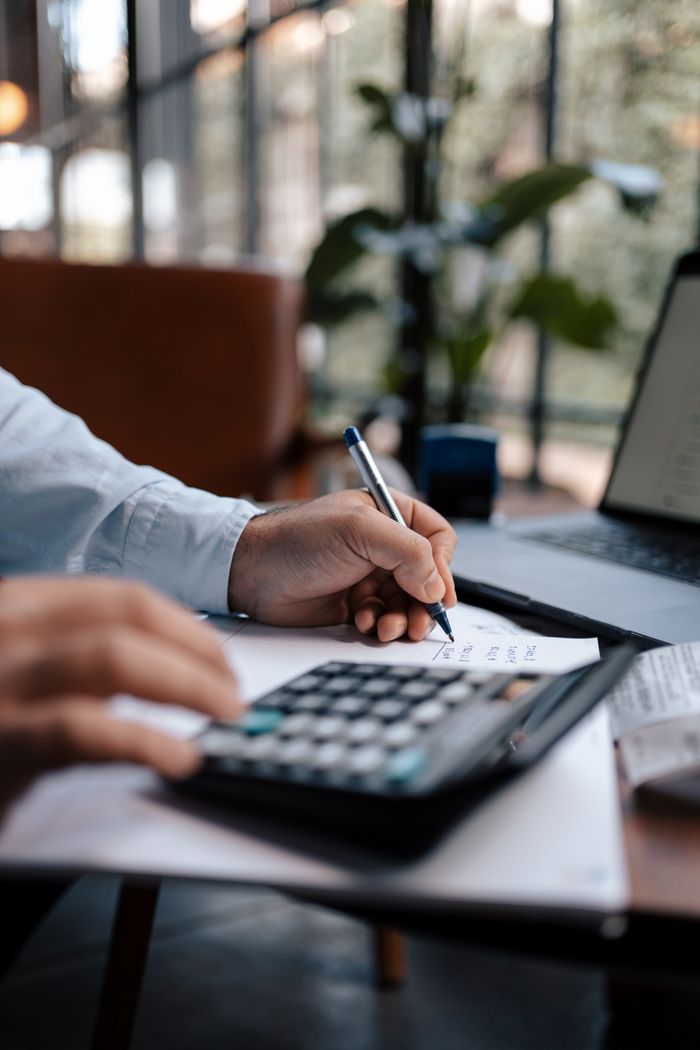 Mastering the First Impression: Your intriguing post title goes here A person calculating finances with a calculator and pen on a desk indoors.